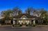 Charming clubhouse facade with elegant features and lush landscaping under a twilight sky.