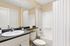 Modern bathroom with sleek fixtures, granite countertop, and a pristine bathtub, exuding elegance and comfort.
