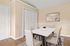 Elegant dining room with a sleek white table, beige chairs, and modern wall art, featuring natural light and a minimalist decor.