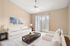 Bright and inviting living room with contemporary decor, featuring a plush white sofa, elegant coffee table, and large window with vertical blinds for abundant natural light.