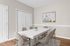 Elegant dining room with a modern white table, comfortable chairs, and chic artwork, complemented by sleek wooden flooring.