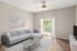 Bright and modern living room with a sleek gray sofa, elegant coffee table, and natural light streaming through sliding glass doors to a balcony.