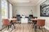 Bright and modern office space featuring stylish wood floors, elegant round tables, and leather chairs, enhanced by natural light from large windows.
