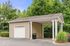 Charming covered parking structure with clean white accents surrounded by lush greenery for a serene residential experience.