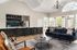 Elegant living area with a modern kitchen, stylish bar seating, plush navy sofa, and abundant natural light.