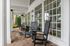 Inviting porch featuring elegant black rocking chairs and large glass-paneled windows, perfect for relaxing afternoons.