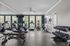Bright and modern fitness center featuring cardio machines and free weights, illuminated by large windows.