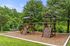 Charming outdoor playground with climbing walls, swings, and slides set against a lush green backdrop, perfect for family enjoyment.