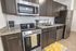 University Pointe, interior, kitchen, wood floor, dark cabinets, stainless steel appliances, stove/oven, dishwasher, refrigerator, lemon floor mat, 'home' 'bon appetit'