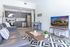 University Pointe, interior, living room, gray leather sofa, black and white area rug, tv, coffee table, kitchen, wood floor, dark cabinets, stainless steel appliances, stove/oven, dishwasher, refrigerator,