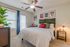 Model apartment bedroom with tan carpet, white walls, a large window and a glass door leading out to the balcony