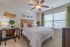 Spacious bedroom with tan carpet, white walls, and a large window looking out at the community
