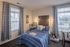 Model apartment bedroom with two large windows facing out at the greenery around the community