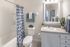 Model apartment bathroom with all white accessories, cabinets, and light brown counter tops.