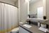 Model apartment bathroom with white cabinetry, gray countertops, and white bathroom facilities