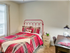 Model bedroom at our apartments in Tuscaloosa, featuring beige carpet, red bedspread, and a window.