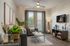 Model apartment living room with hard wood style flooring, flat screen tv, gray couch and armchair, and wood tables