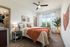 Model apartment bedroom with tan carpet, full size bed, and a wood nightstand and dresser