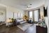 Model apartment living room with hard wood style flooring and gray couch, armchair, wooden side table, and coffee table