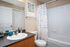 Model bathroom at our apartments near UCF, featuring a shower and bath combo and wood grain cabinetry.