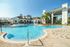 The pool lounge at our apartments for rent in Orlando, Florida, featuring beach chairs, umbrellas, and ping pong table.