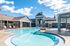 The pool area at our apartments for rent near Penn State, featuring beach chairs, umbrellas, and a clubhouse.