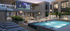 Luxurious apartment complex with a stylish outdoor lounge area, inviting pool, and large outdoor screen, perfect for entertaining and relaxation.