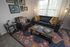 Charming living room with a cozy dark leather sofa, stylish patterned pillows, vibrant bohemian rug, and modern wall art, creating a warm and inviting ambiance.
