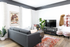 Chic living room with sleek gray sofa, vibrant red patterned rug, modern entertainment center, and stylish wall art.