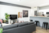 Modern living room with sleek gray sofa, stylish wall art, and open kitchen featuring elegant bar seating.