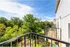 Charming balcony view of lush green trees under a bright blue sky, offering a serene and refreshing environment.