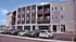Modern three-story apartment complex with spacious balconies and ample parking in a vibrant neighborhood setting.