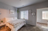 Bright and cozy bedroom with modern decor, featuring a comfortable bed, elegant artwork, and natural light from large windows.