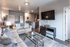 Chic open-concept living room with plush sofas, elegant glass coffee table, wall-mounted TV, and modern kitchen in the background.