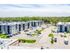Aerial view of modern apartment complex surrounded by lush greenery, featuring spacious parking and contemporary architecture.