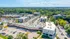 Vibrant aerial view of Red Cedar Flats and surrounding residential area, showcasing modern apartment buildings, ample parking, and lush green landscape under a clear blue sky.