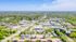 Vibrant aerial view of a lush green community with modern apartments, shopping centers, and tree-lined streets.