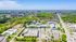 Vibrant aerial view of a bustling cityscape with lush greenery, commercial buildings, and sprawling residential areas, showcasing a perfect blend of urban and natural beauty.