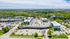 Charming aerial view of a vibrant residential and commercial complex surrounded by lush greenery, showcasing comfortable apartment buildings and convenient shopping in a serene setting.