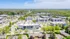 Vibrant aerial view of a modern apartment complex surrounded by lush greenery and wide streets, showcasing a perfect blend of urban and natural living.