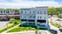 Chic Red Cedar Flats building surrounded by lush greenery, offering modern apartments above convenient retail spaces.