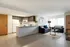Bright and modern open-concept living room and kitchen with sleek cabinetry, cozy seating, and abundant natural light.