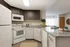 Modern kitchen with sleek white appliances, granite countertops, and stylish cabinetry, opening into a bright and inviting living area.