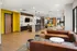 Modern co-working space with sleek leather sofas, vibrant yellow accents, and stylish lighting fixtures for a dynamic working environment.