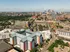Aerial view of a vibrant urban neighborhood with modern apartment buildings, lush greenery, and a bustling city skyline in the background.