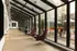 Spacious and modern sunlit hallway with floor-to-ceiling windows, elegant seating, and views of a stylish outdoor patio.