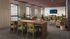 Contemporary co-working space with elegant wooden desks, comfy seating, and lush green plants, bathed in natural light from large windows.