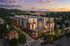 Charming aerial view of a modern apartment complex with stylish architecture, vibrant surroundings, and scenic sunset backdrop.