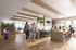 Modern communal kitchen space with warm wood accents, pendant lighting, and abundant natural light; features people enjoying conversation and leisure activities at a spacious island and cozy seating area.