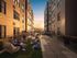 Modern urban courtyard with vibrant social space featuring comfortable seating, ambient string lights, and lush greenery.